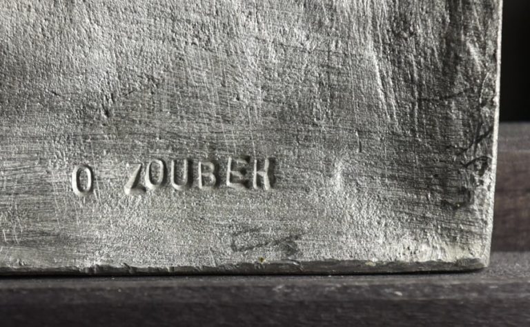 Střední cínový reliéf Učitel je výřezem z velkého cínové reliéfu Učitel a Žákyně. Ten vznikl v roce 1997 a později z něj Olbram Zoubek vytvořil i zmiňovaný výřez.