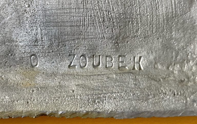 Střední cínový reliéf Adam, Eva, had  z dílny Olbrama Zoubka zachycuje oblíbený biblický motiv Olbrama Zoubka- Adama, Evu a hada, který Evě nabízí jablko poznání. Je to klasický tzv. střední formát cínového reliéfu o rozměru 30 x 21 cm. Postava Adama a Evy velmi plasticky vystupují z podkladu, vlasy Evy stejně jako celý had jsou velmi silně značeny Cínový reliéf Adam, Eva, had  z roku 1992 je signován značkou O. Zoubek vyraženou na rubové straně reliéfu.